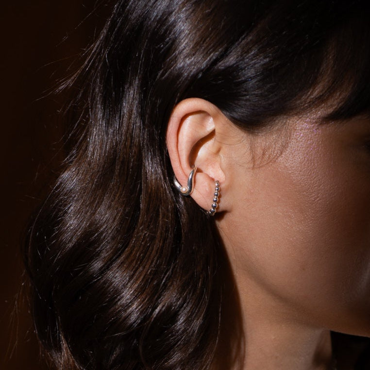 Bague d’oreille en argent sterling ondulée avec perle portée à l’oreille.