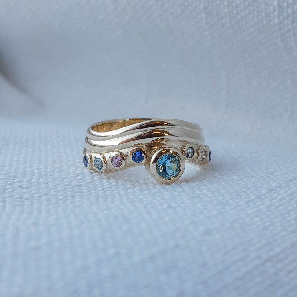 Cette bague a été fabriquée en répliquant les couleurs de chaque pierres qui étaient présente sur la bague familliale originale. Et l'or de la bague originale a été recyclée.